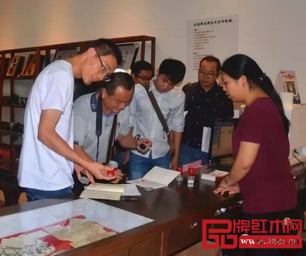 在红木主题邮局内，采编人员纷纷在本子上盖下印章