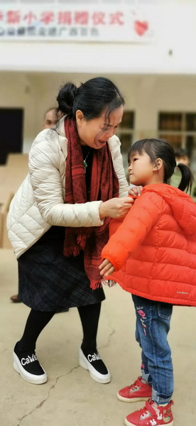 东成红木副董事长林霞为孩子们穿上温暖的棉衣
